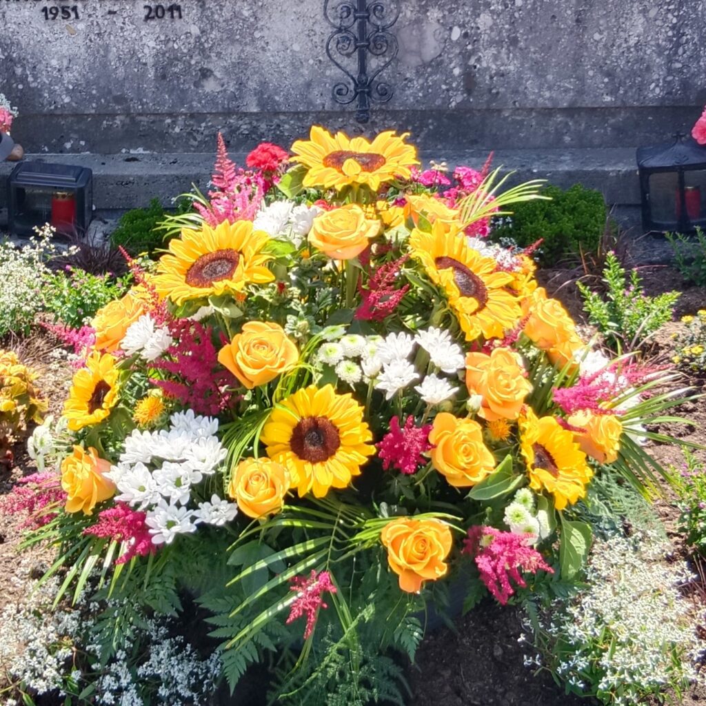Trauergesteck mit Sonnenblumen und pinken Blüten – Vöcklabruck